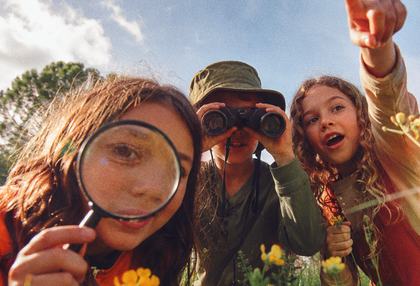 Niñas observando el campo con lupa y prismáticos